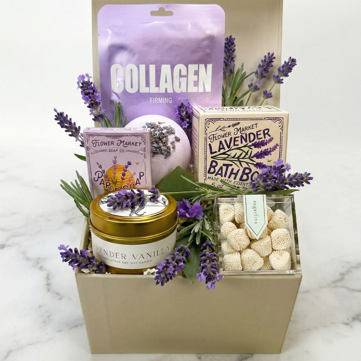 Mini Lavender Spa Gift Box set featuring a candle, bath bomb, mask, and a sweet treat on a white marble surface 