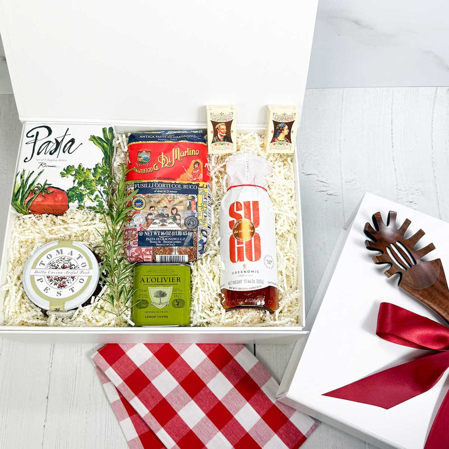 ekuBOX gift box with Italian-themed products including pasta and olive oil, pasta sauce, dipping dishes on a white background. White box with pasta spoon and a red ribbon.