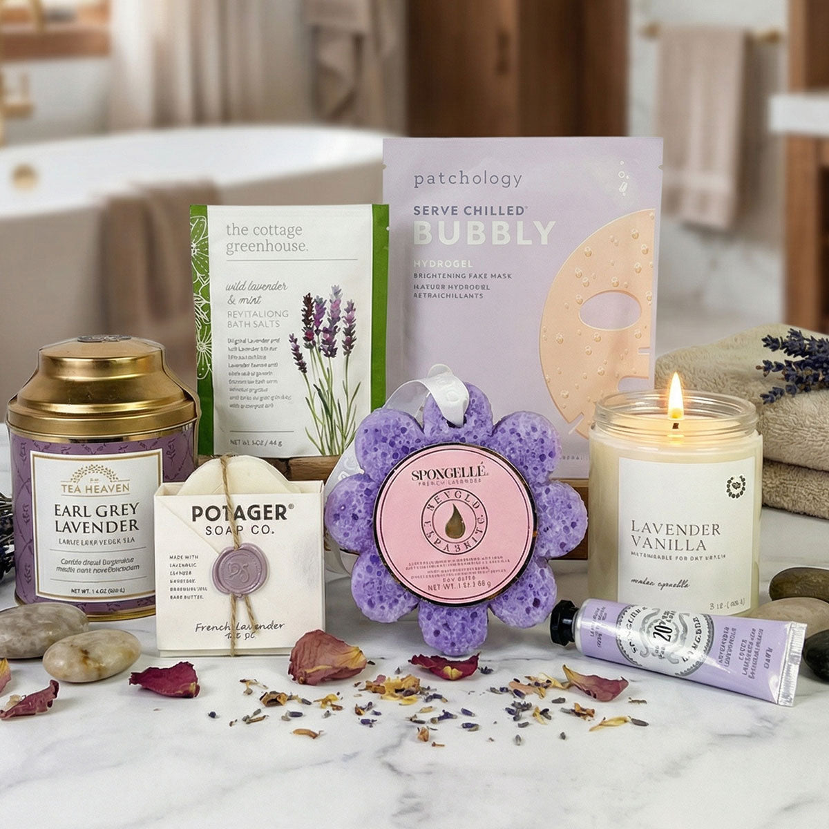 Collection of bath and body products including a candle, soap, and scrubber on a marble surface.