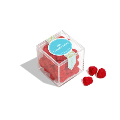 Clear cube container by Sugarfina filled with red raspberries gummies on a white background