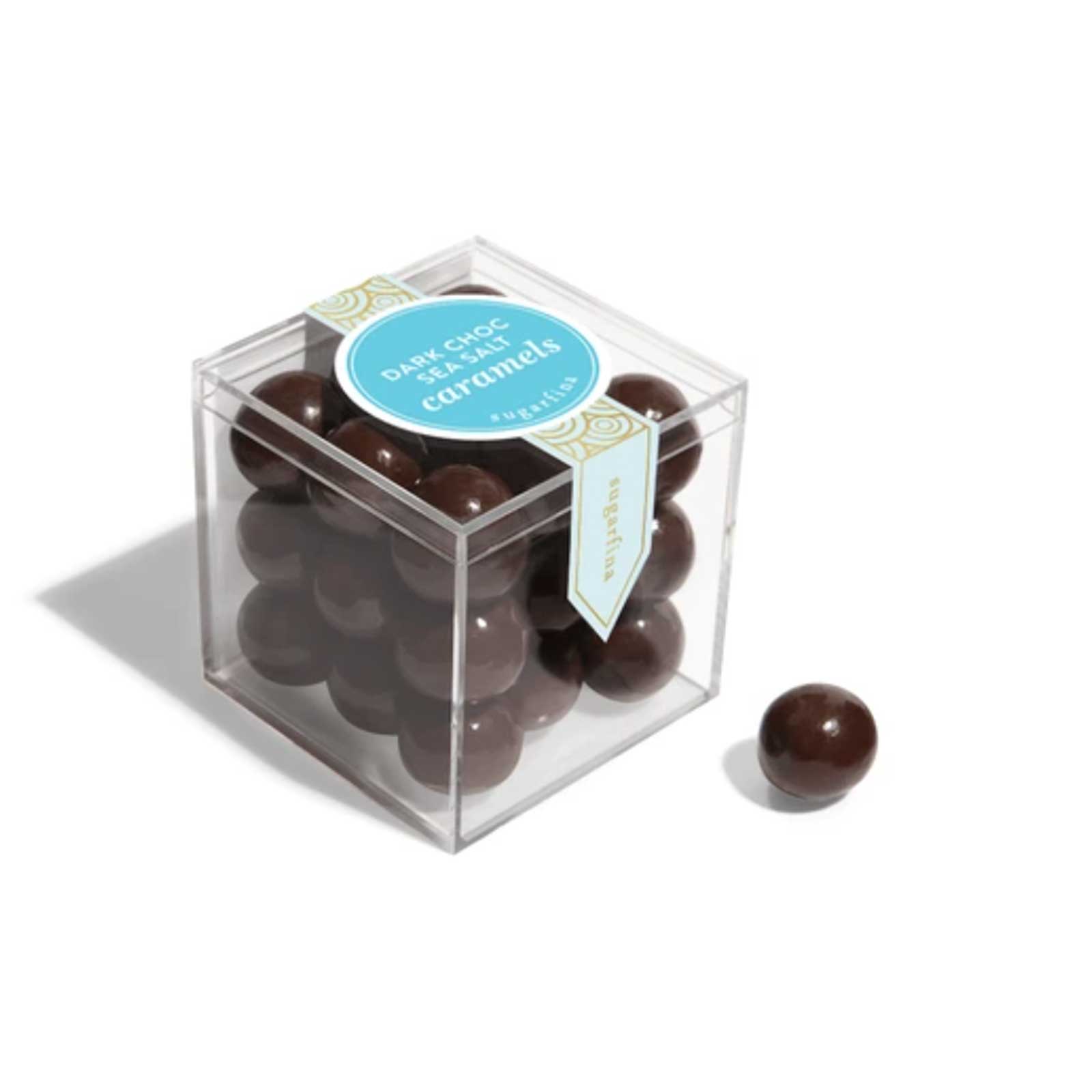 Clear cube box filled with chocolate caramels on a white background