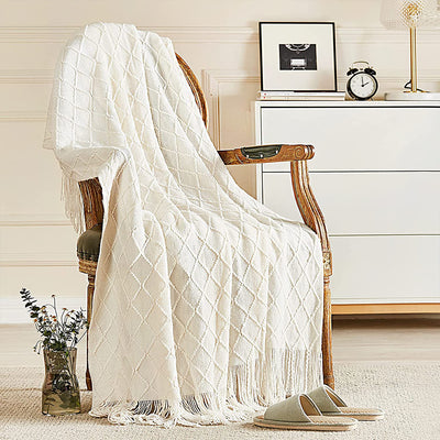 White textured throw blanket draped over a wooden chair in a room with decor elements.