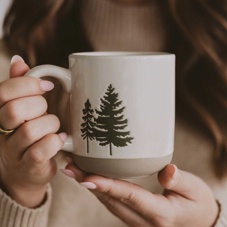 Person holding a mug with tree design